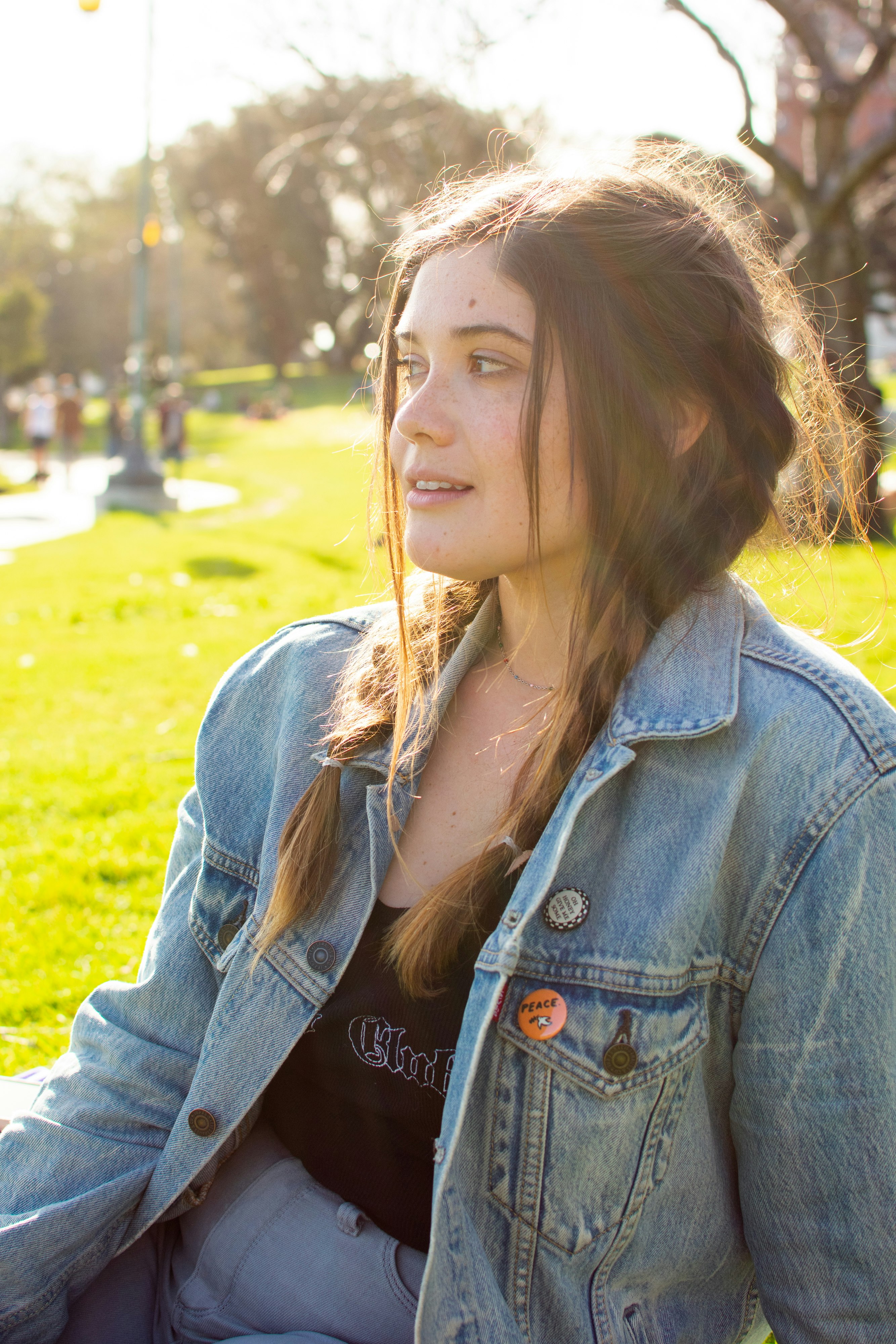 woman in blue denim jacket standing on green grass field during daytime